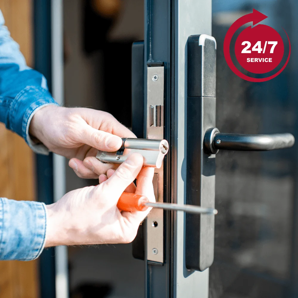 Changement de serrure par un professionnel, gros plan sur une main tenant un tournevis devant une porte.